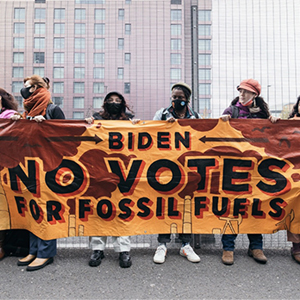 Protesters holding a sign that reads: Biden No Votes for Fossil Fuels