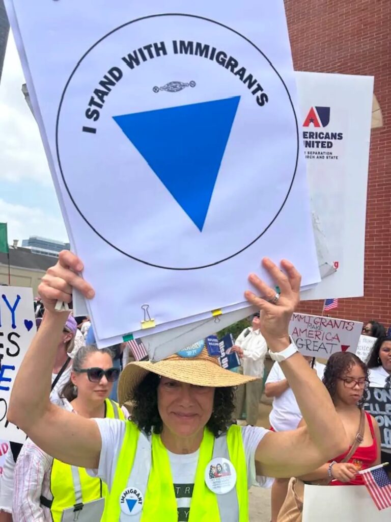 Displaying the blue triangle as a symbol of solidarity with immigrants during a march in Dallas, TX. Photo/Witness at the Border.